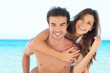 Happy couple piggyback at beach