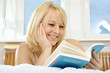 Junge Frau liest Buch im Bett