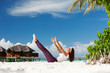 Pretty woman doing yoga exercises on the beach
