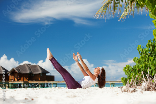 Photo: Pretty woman doing yoga exercises on the beach Pretty woman doing yoga exercises on the beach
