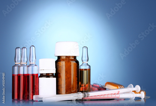 Photo: medical ampules, bottles, pills and syringes on blue background medical ampules, bottles, pills and syringes on blue background