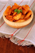 Appetizing village potatoes in bowl on wooden table close-up