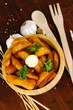 Appetizing village potatoes in bowl on wooden table close-up