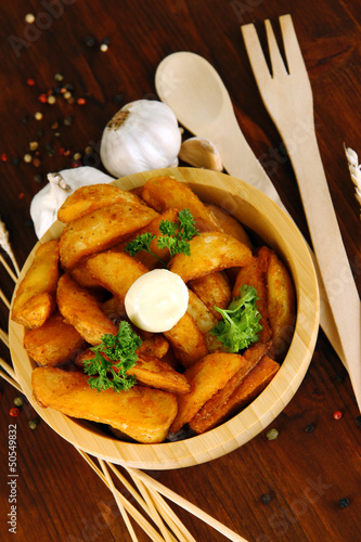 Photo: Appetizing village potatoes in bowl on wooden table close-up Appetizing village potatoes in bowl on wooden table close-up