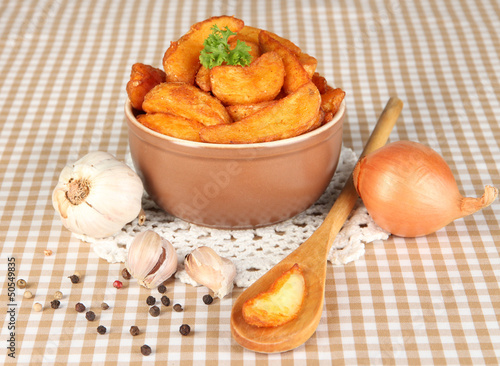 Photo: Appetizing village potatoes in bowl on beige tablecloth Appetizing village potatoes in bowl on beige tablecloth