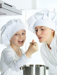 Mother and child having fun in the kitchen to taste a soup