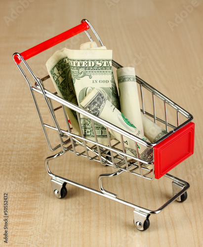 Photo: Money in cart on wooden table close-up Money in cart on wooden table close-up