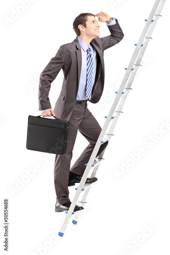 Photo: Full length portrait of a businessman with briefcase climbing a Full length portrait of a businessman with briefcase climbing a