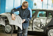 repairman sanding plastic car bumper