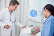 Foto: Doctor and nurse checking patient lying under digital screen sho Doctor and nurse checking patient lying under digital screen sho