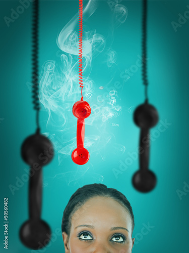 Photo: Woman looking up at hanging telephone receiver Woman looking up at hanging telephone receiver