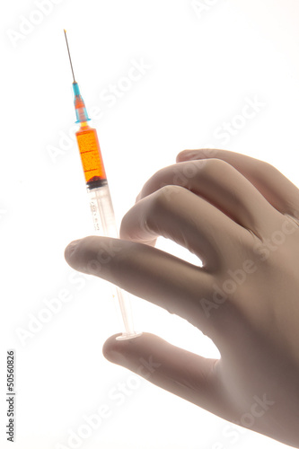 Photo: Gloved hand holding a syringe Gloved hand holding a syringe