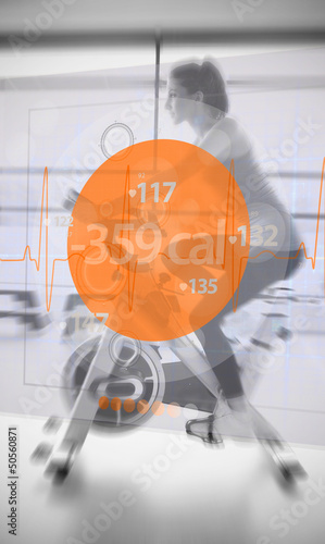 Photo: Woman riding exercise bike with futuristic interface showing los Woman riding exercise bike with futuristic interface showing los