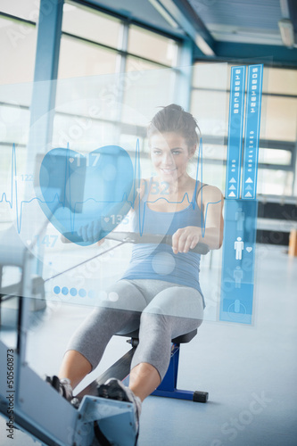 Photo: Young girl doing rowing machine with futuristic interface Young girl doing rowing machine with futuristic interface