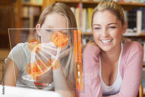 Photo: Two smiling students looking at laptop and futuristic interface Two smiling students looking at laptop and futuristic interface