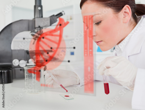 Photo: Scientist pouring drop of blood onto glass with futuristic inter Scientist pouring drop of blood onto glass with futuristic inter