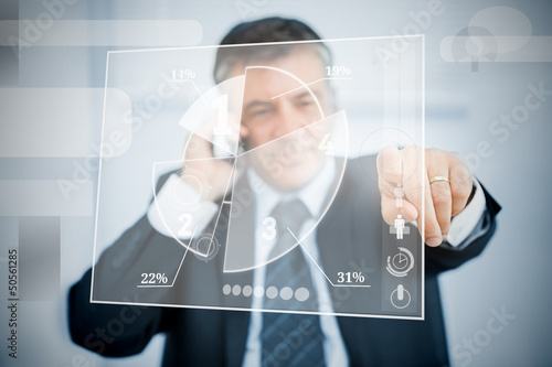 Photo: Businessman using transparent pie chart interface Businessman using transparent pie chart interface
