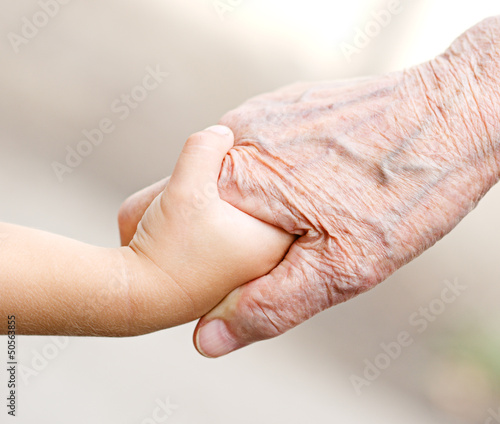Photo: An old woman and a kid holding hands together An old woman and a kid holding hands together