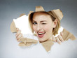 Woman blinks one´s eyes looking through paper hole