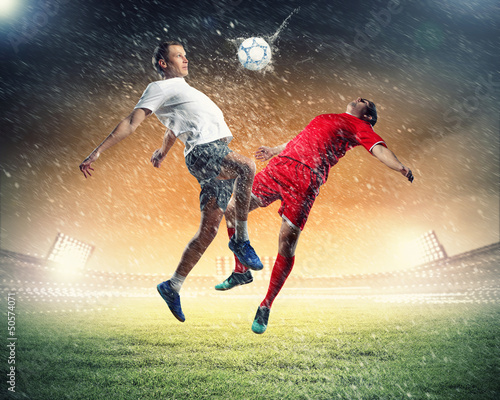 Photo: two football players striking the ball two football players striking the ball