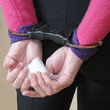 Woman in police issue handcuffs holding drugs