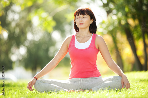 Photo: Pretty woman doing yoga exercises in the park Pretty woman doing yoga exercises in the park