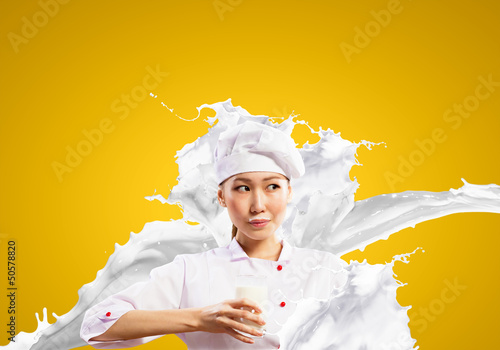 Photo: Asian female cook against milk splashes Asian female cook against milk splashes