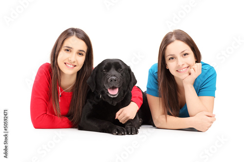 Photo: Two young females lying and posing with a dog Two young females lying and posing with a dog