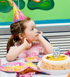 The girl at the holiday table. Cake with a candle