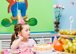 The girl at the holiday table. Cake with a candle