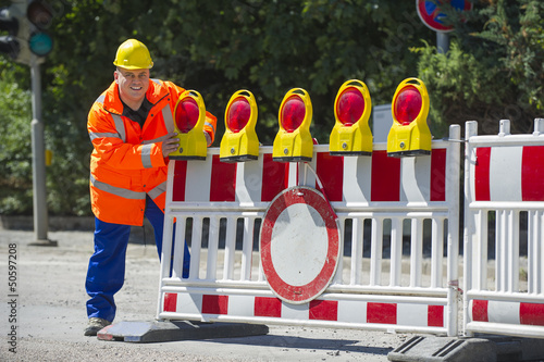 Photo: Arbeiter überprüft die Baustellenabsperrung Arbeiter überprüft die Baustellenabsperrung