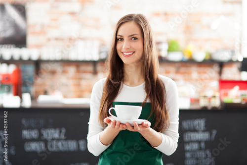 Photo: Waitress holding cup of coffee in cafe Waitress holding cup of coffee in cafe