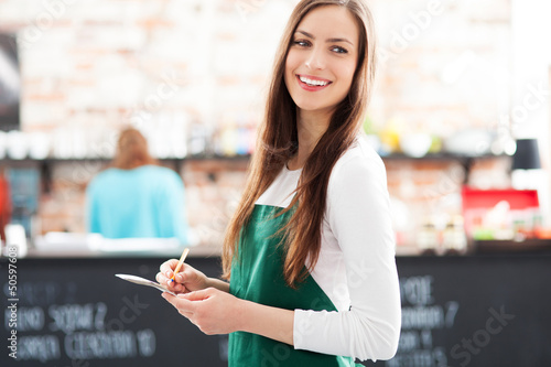 Photo: Young waitress holding notepad in cafe Young waitress holding notepad in cafe