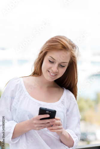 Photo: junge frau schaut auf ihr smartphone junge frau schaut auf ihr smartphone