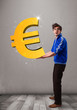 Good-looking boy holding a big 3d gold euro sign