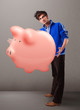 Handsome man holding a huge savings piggy bank