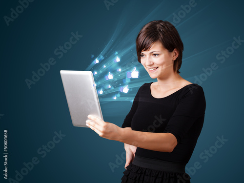 Photo: Young woman looking at modern tablet with abstract lights and so Young woman looking at modern tablet with abstract lights and so