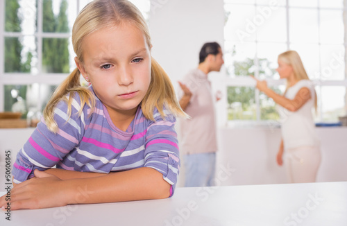 Photo: Little girl looking sad in front of fighting parents Little girl looking sad in front of fighting parents