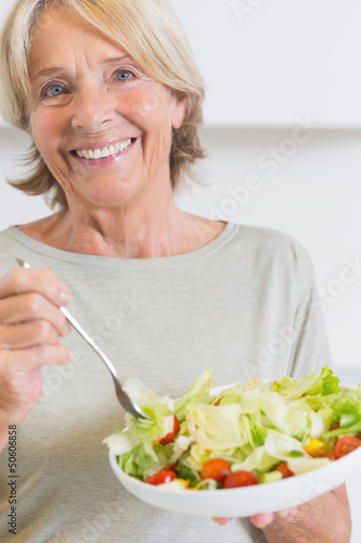 Photo: Happy mature woman eating salad Happy mature woman eating salad