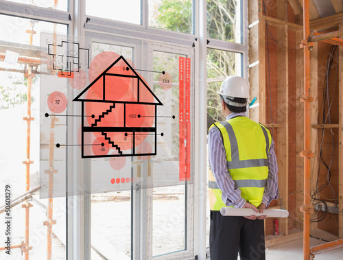 Photo: Architect looking out window with red hologram interface in fore Architect looking out window with red hologram interface in fore