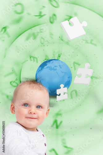 Photo: Portrait of a baby with planet and jigsaw pieces green backgroun Portrait of a baby with planet and jigsaw pieces green backgroun