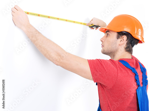 Photo: Construction worker measuring the wall Construction worker measuring the wall