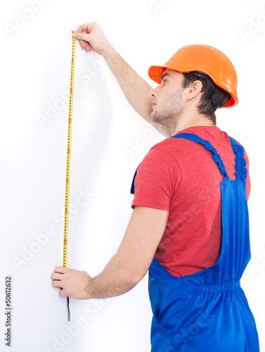 Photo: Construction worker measuring the wall Construction worker measuring the wall