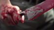 Close up of man gripping bloody knife with blood dripping