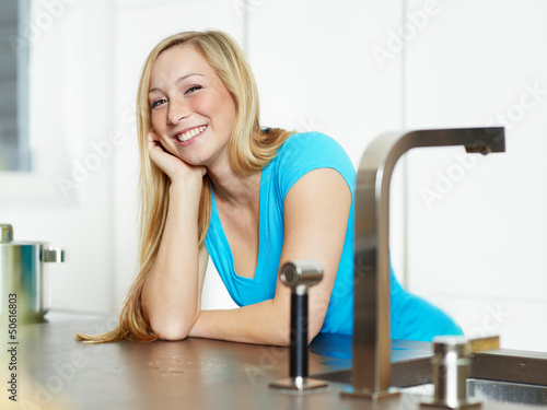 Photo: Smiling young woman stands at the kitchen counter Smiling young woman stands at the kitchen counter