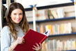 Young student reading a book in a library