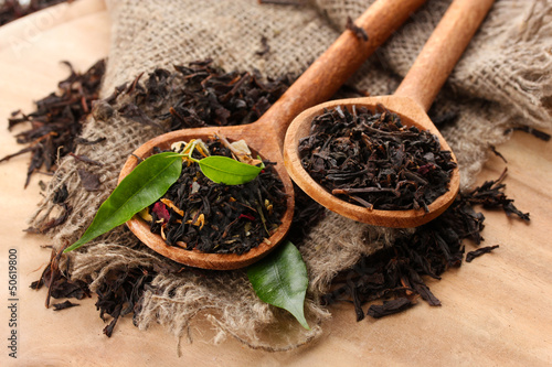 Photo: Dry tea with green leaves in wooden spoons, on wooden Dry tea with green leaves in wooden spoons, on wooden