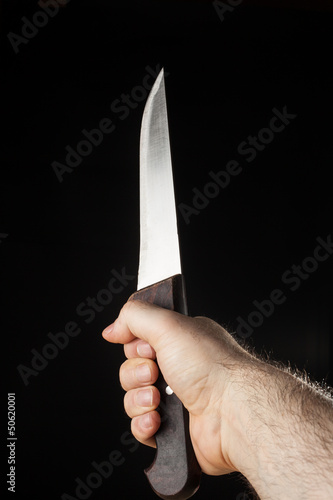 Photo: Hairy male hand holding a knife over a black background Hairy male hand holding a knife over a black background