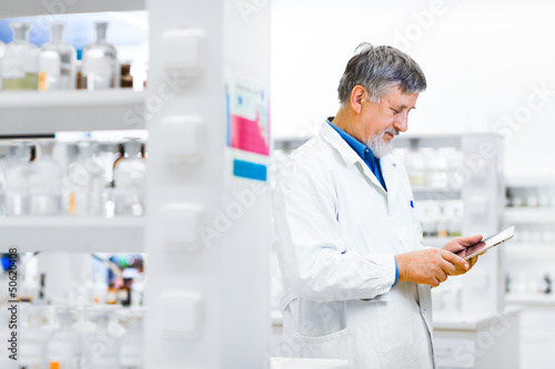 Photo: Senior doctor/scientist using his tablet computer at work Senior doctor/scientist using his tablet computer at work