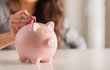 Photo: Woman Putting Coin In Piggy Bank Woman Putting Coin In Piggy Bank